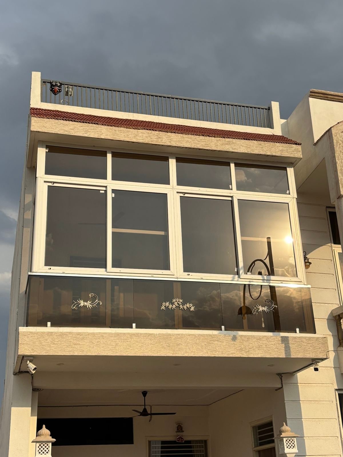 Balcony enclosed with white UPVC sliding windows, fixed top panels and a tinted glass railing
