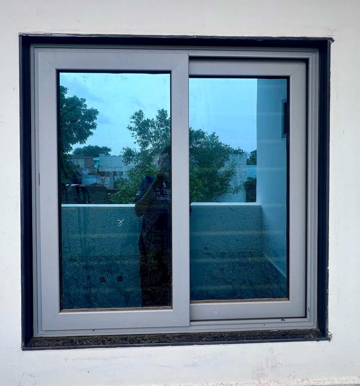 Grey UPVC two-track sliding window fitted in a white wall